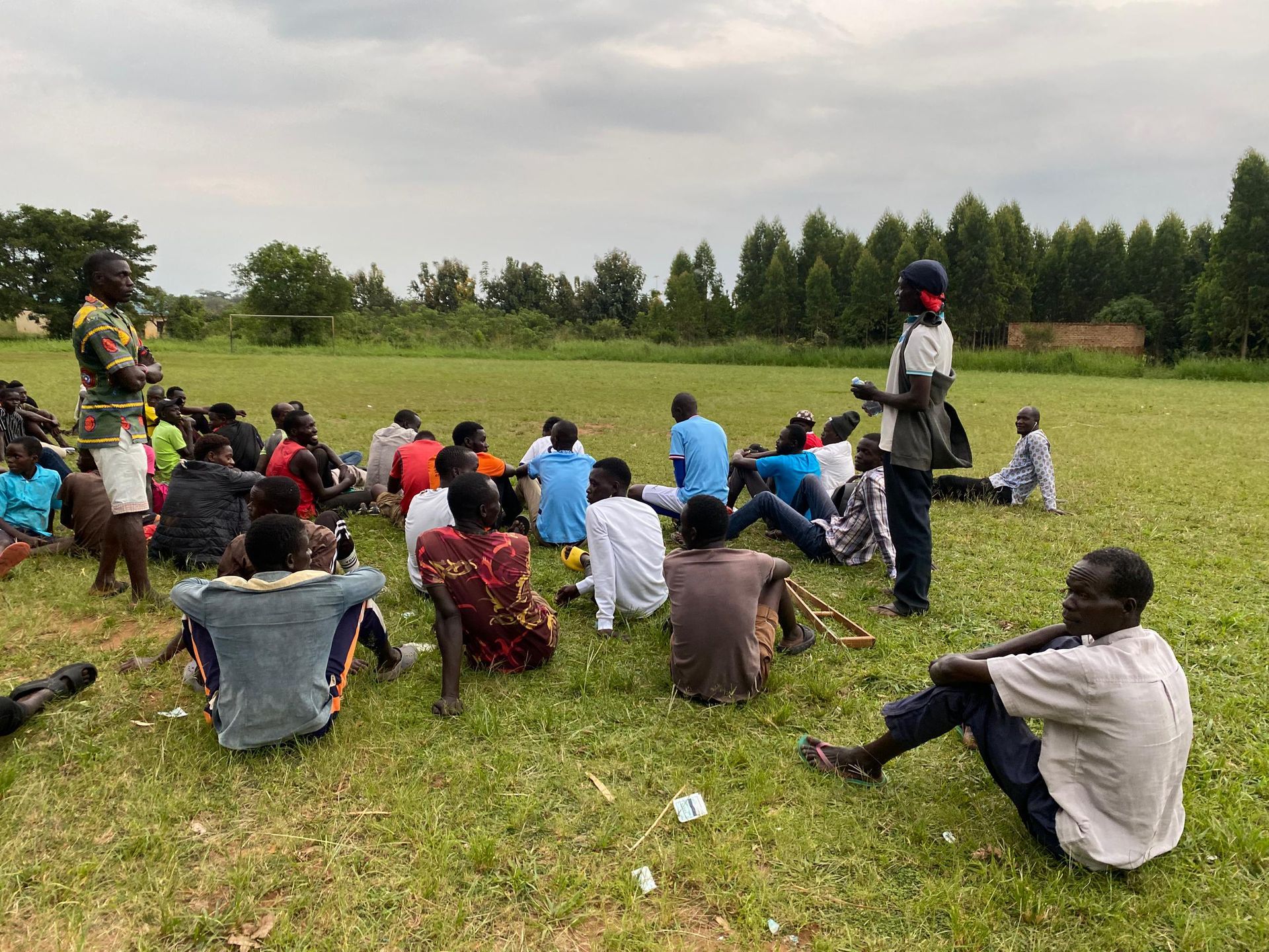 A group of people are sitting on the grass in a field.