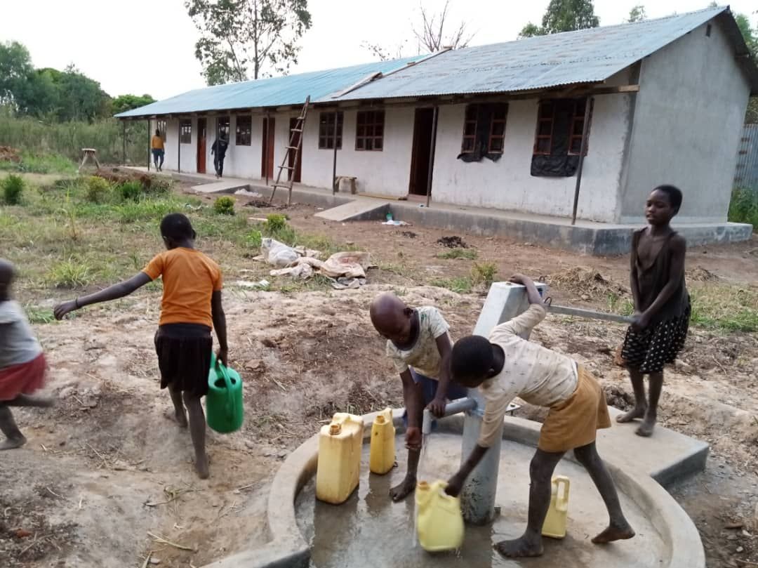 A group of people are gathered around a water pump