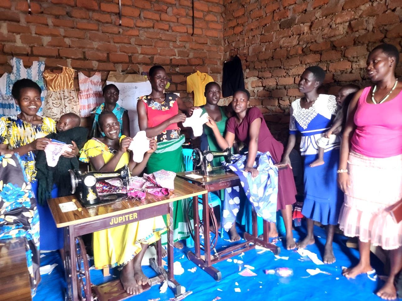 A group of people standing around a sewing machine that says singer on it
