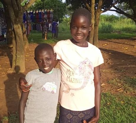 A boy and a girl are posing for a picture in a field.