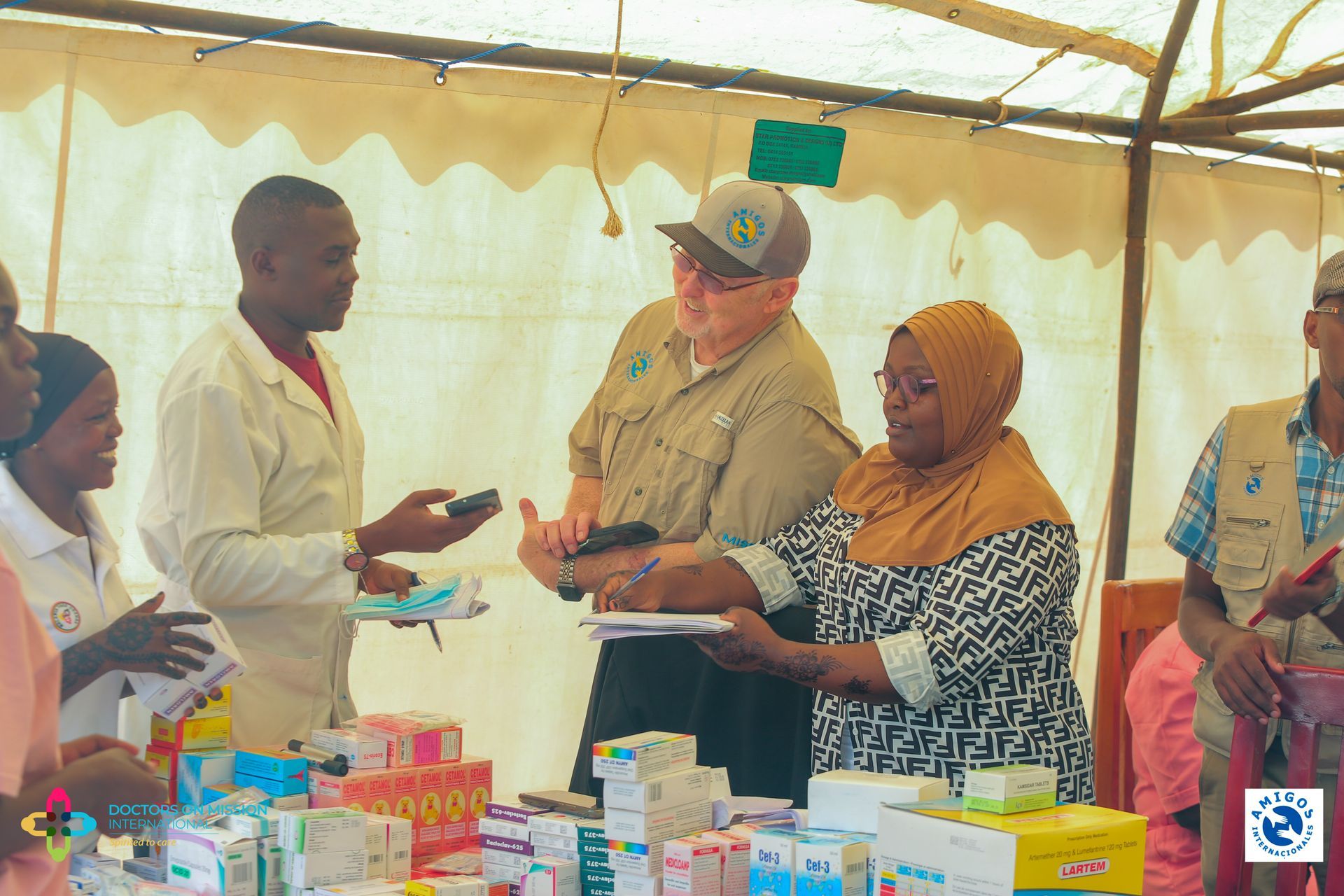People at a medical clinic. A man examines supplies while others assist patients.
