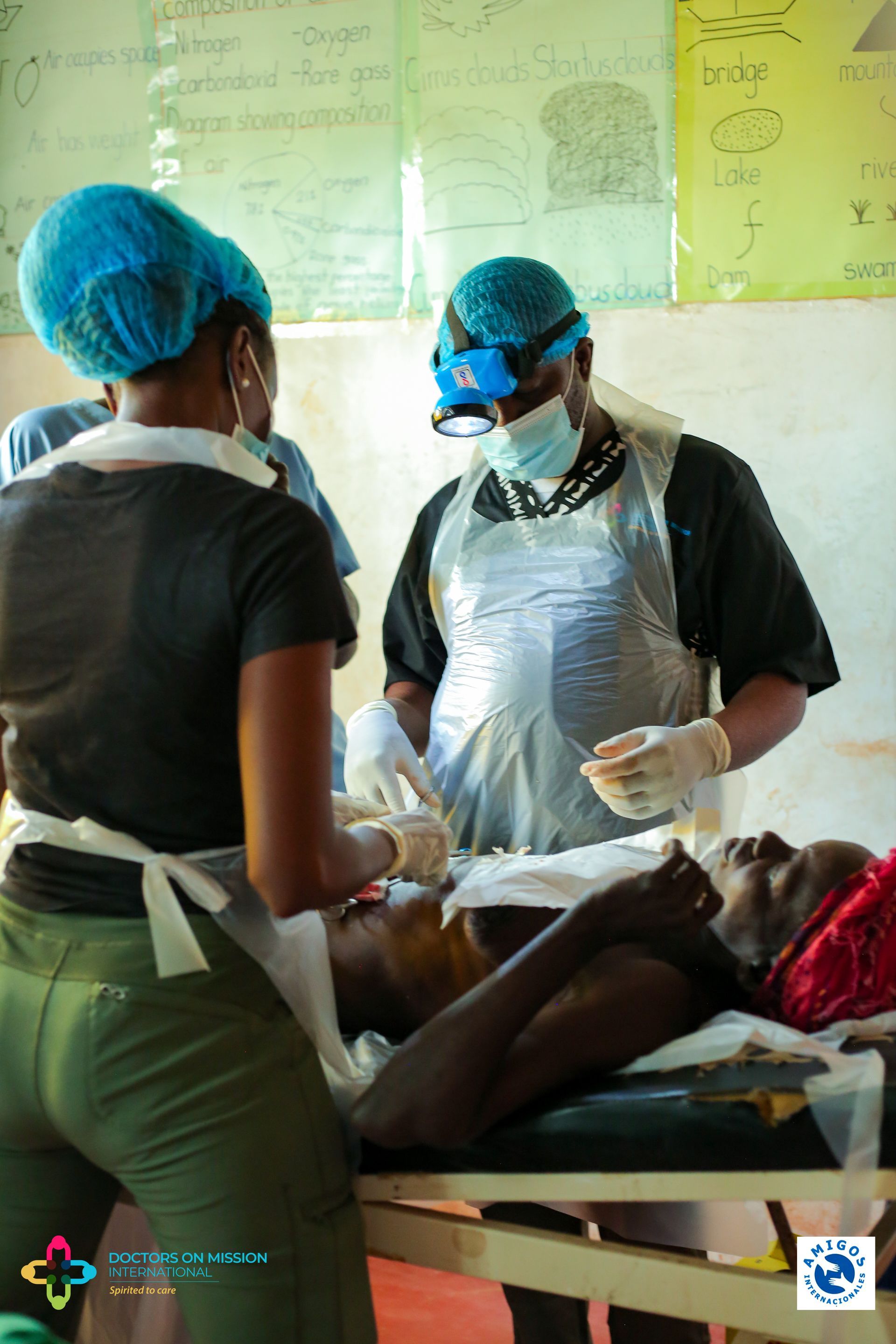 A man is laying in a hospital bed while two nurses work on him.