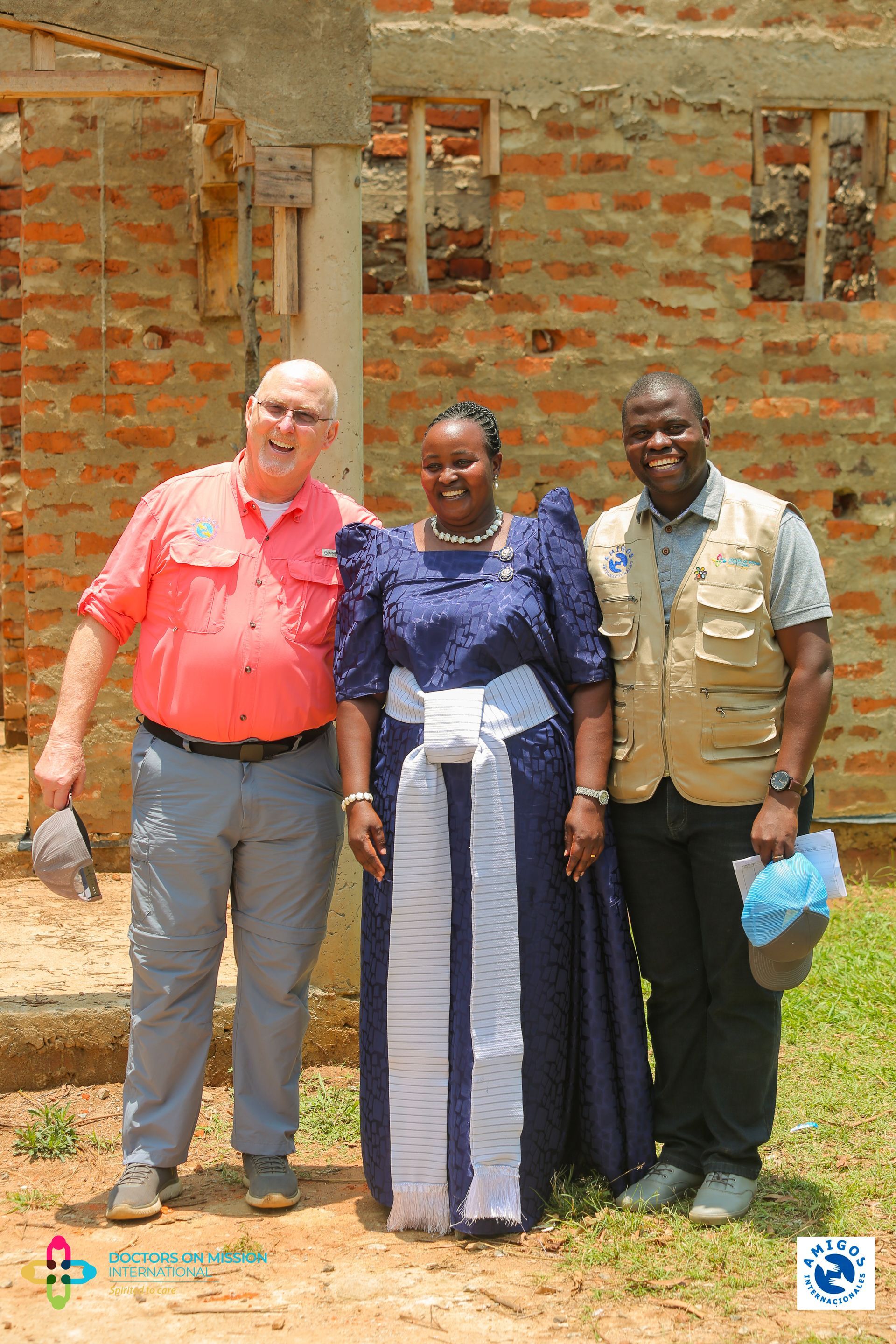 Three people are posing for a picture in front of a brick building.
