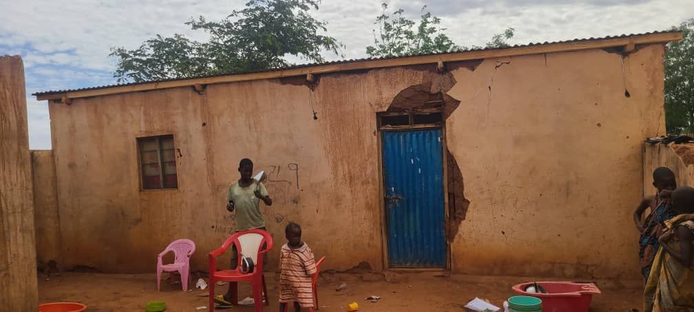 A group of people are standing in front of a building with a blue door.