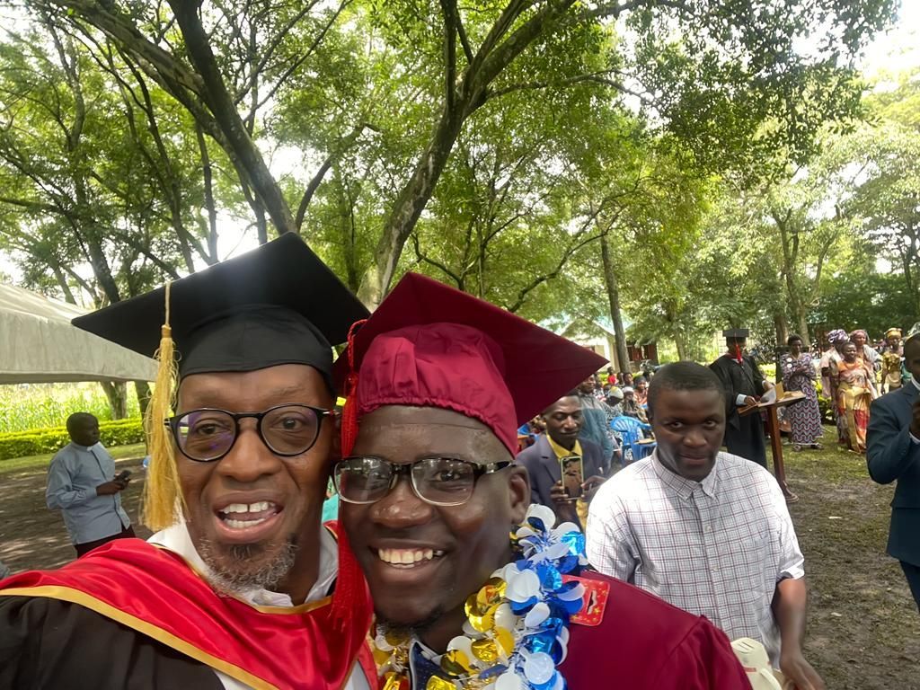 two men in graduation caps and gowns are posing for a picture .