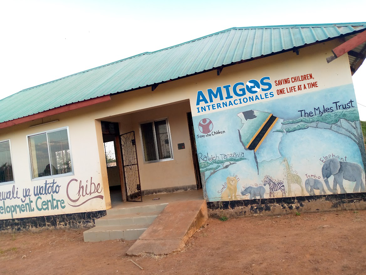 A building with a green roof and a mural on the side that says amigos