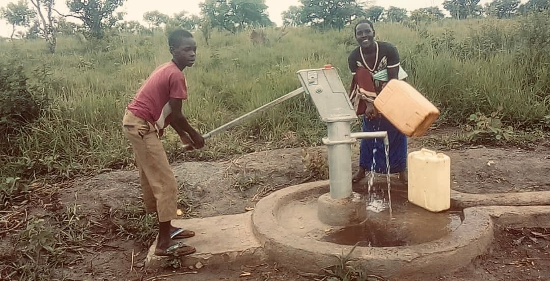 Two refugee children pumping water from a well provided by Amigos Internacionales