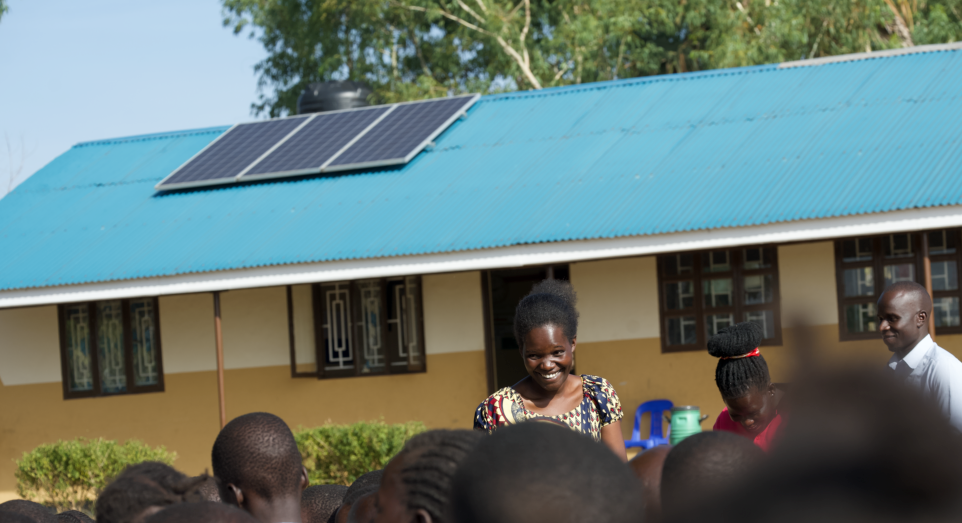 A group of people are standing in front of a building with solar panels on the roof.