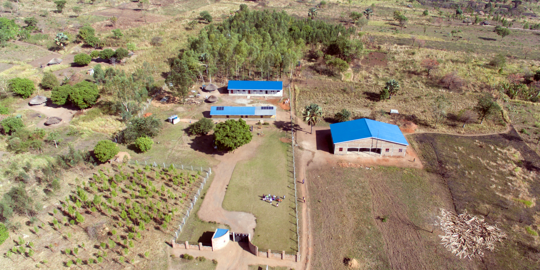 An aerial view of a farm with a blue building in the middle of the field.