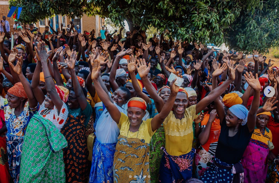 A large group of people are standing together with their hands in the air.