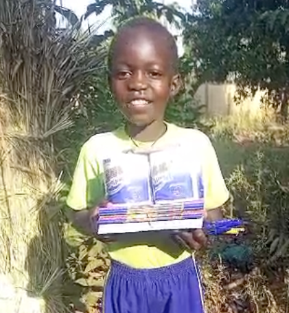 A young boy is holding a stack of books in his hands.