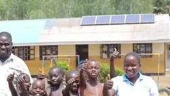 A group of children are giving a thumbs up in front of a school building.
