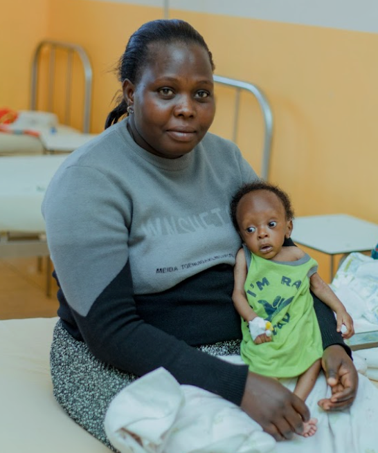 A group of children are peeking over a red fence.