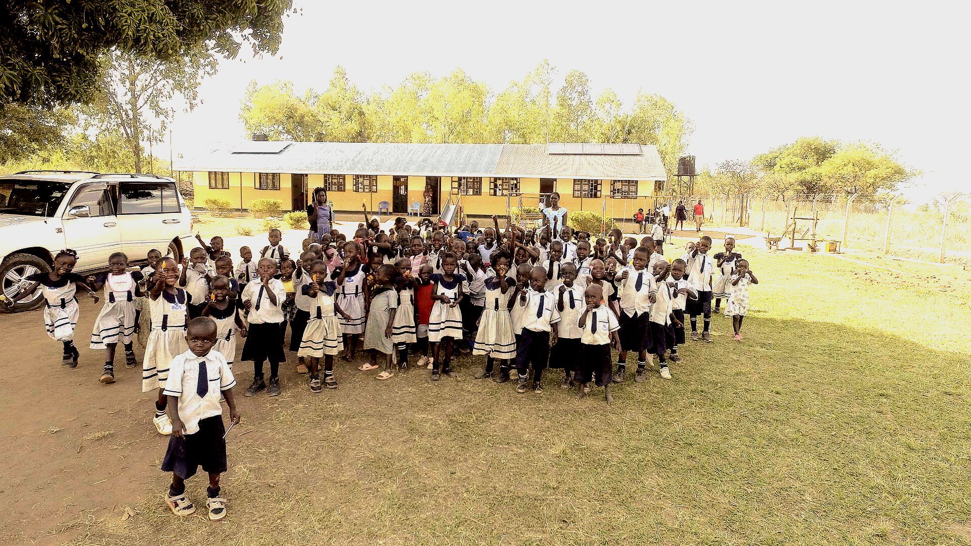 A large group of children are standing in front of a school bus