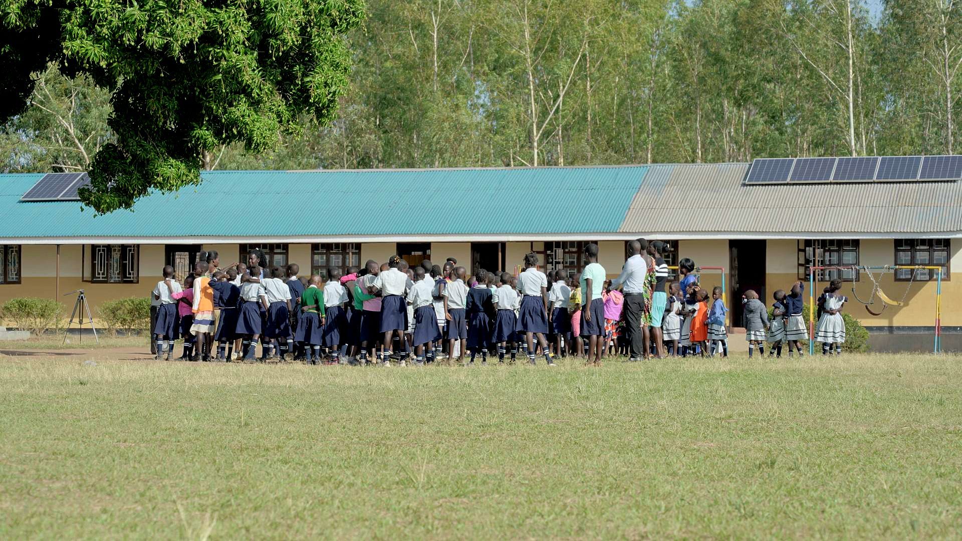 A group of children are standing in front of a school building.