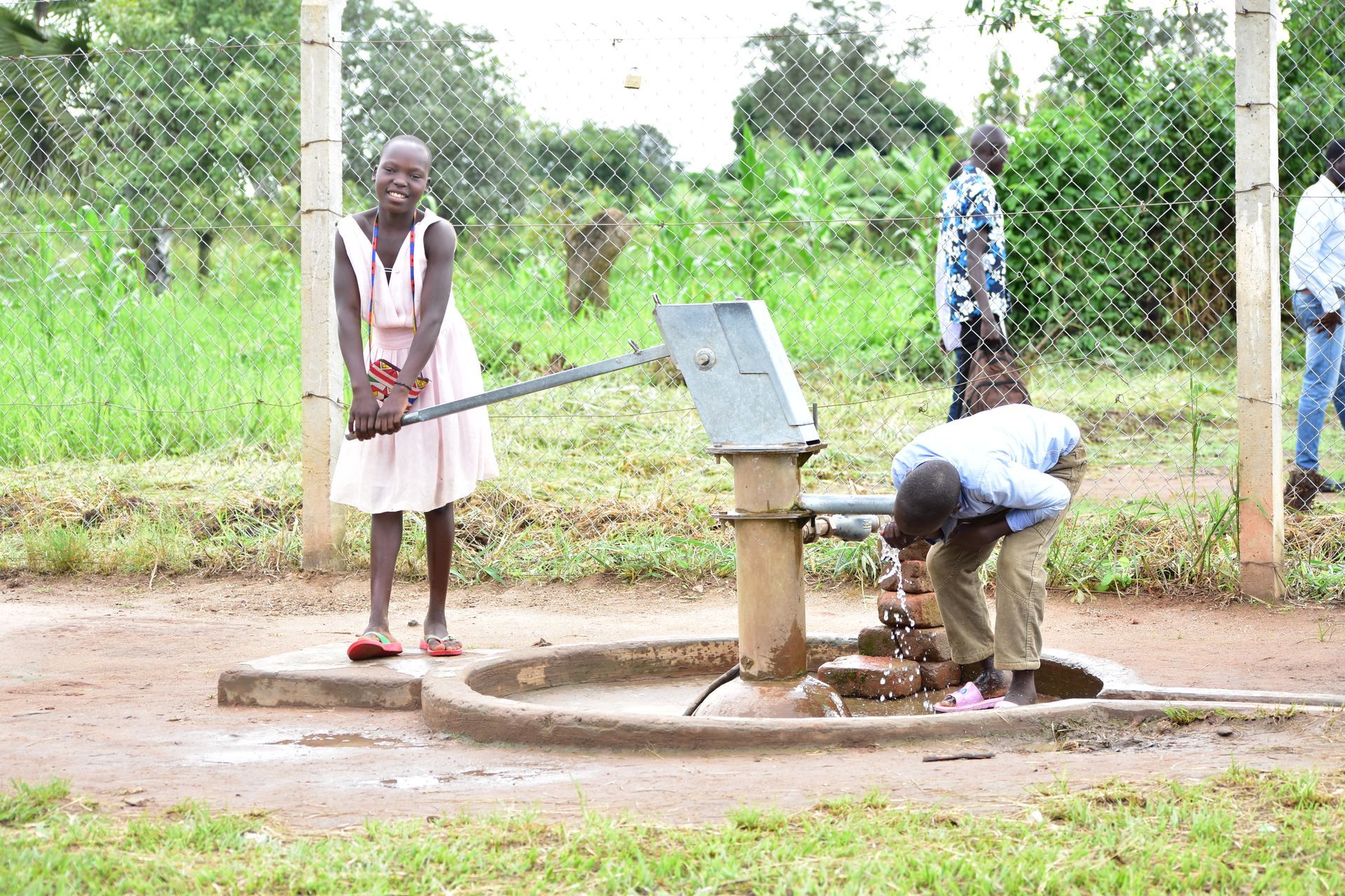 A man and a girl are working on a water pump in a field.