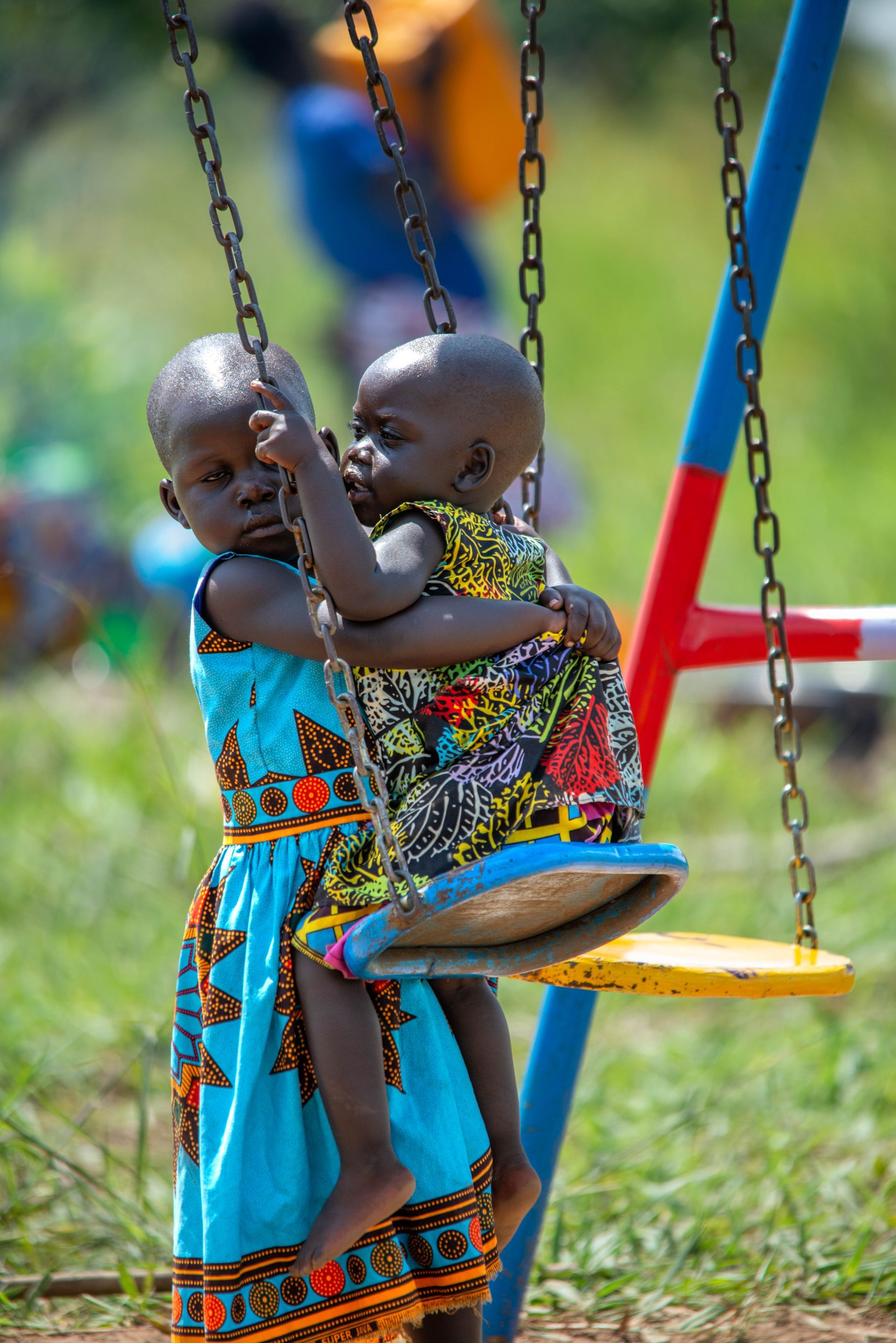 Two little girls are sitting on a swing together