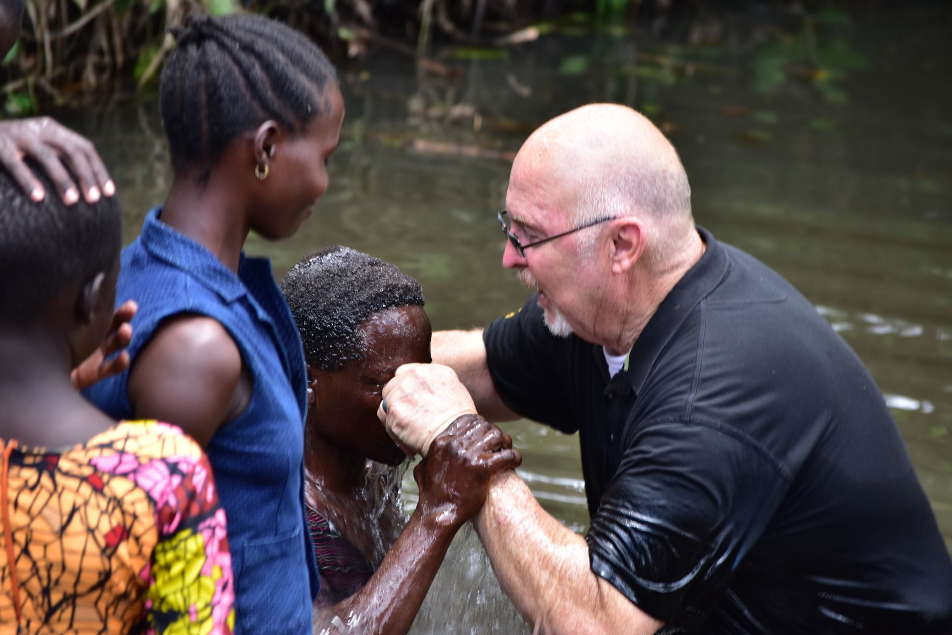 CEO Michael Ryer is baptizing a young girl in a river.