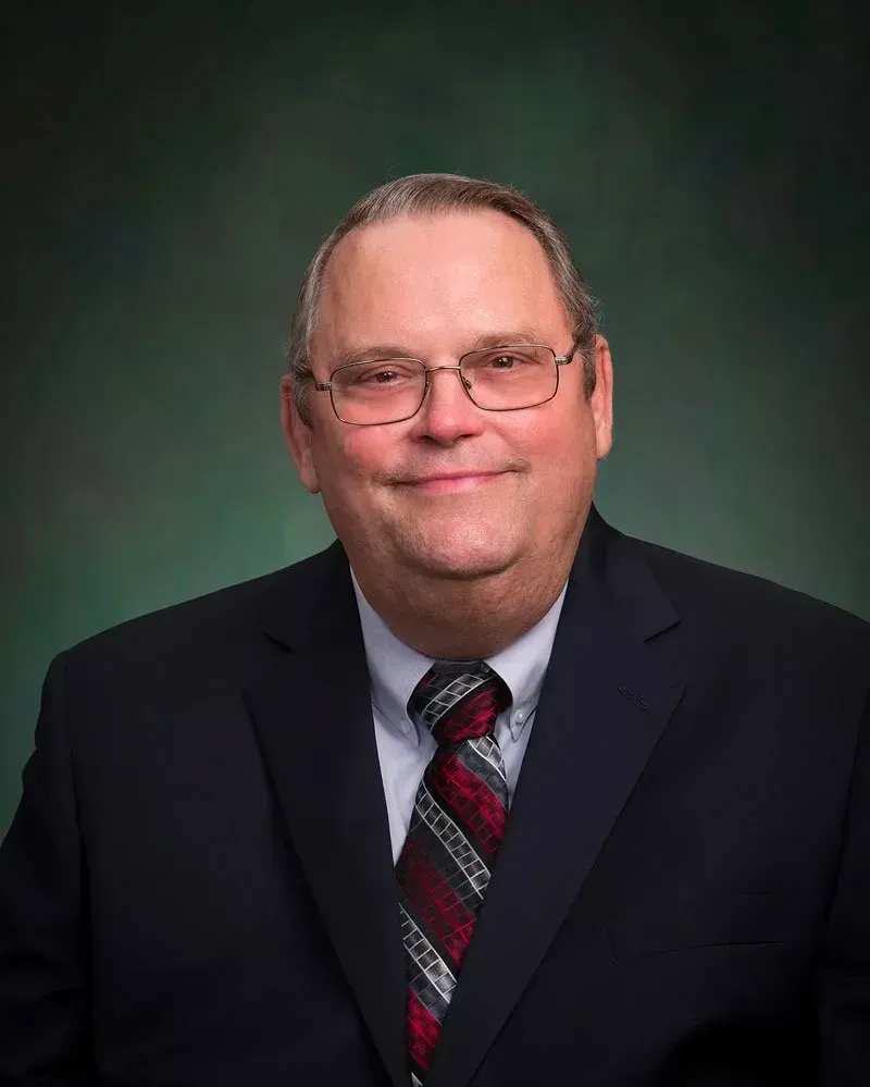 A man in a suit and tie is smiling for the camera.