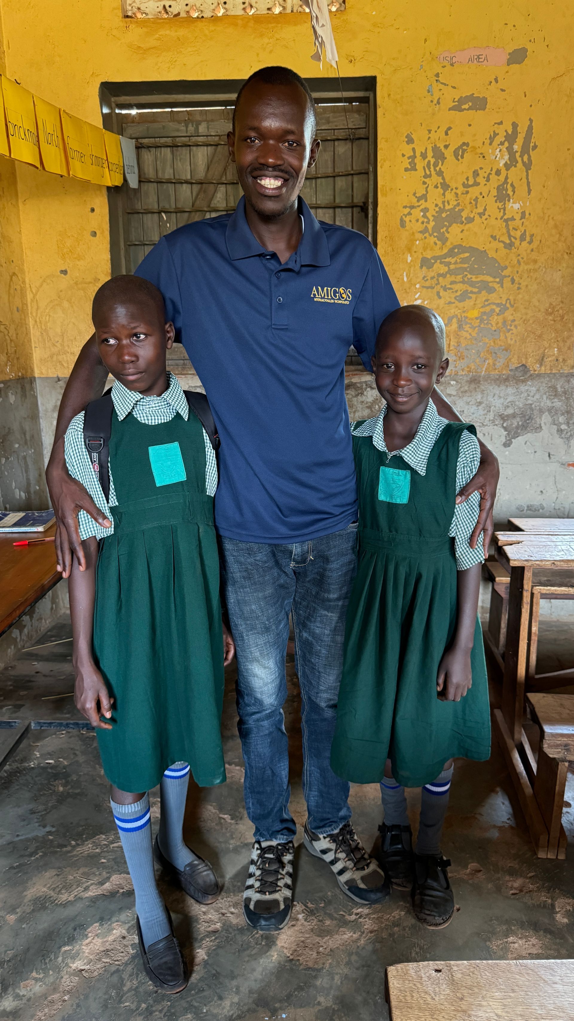 A man is standing next to two little girls in a classroom.