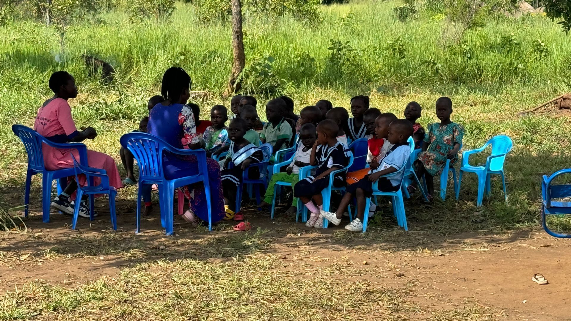 A group of children are sitting in a circle in a field.