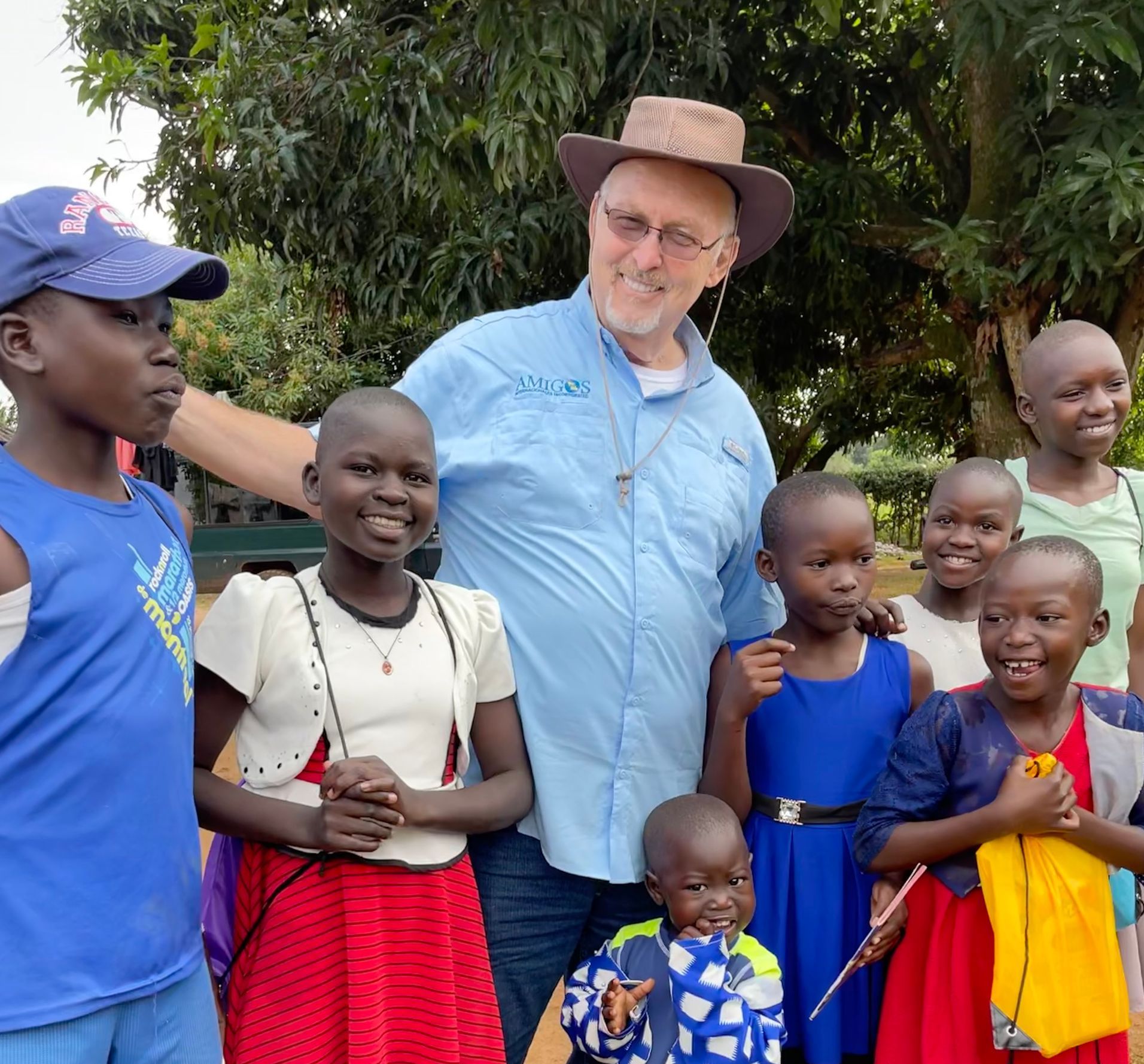 a group of children are posing for a picture with a man wearing a hat