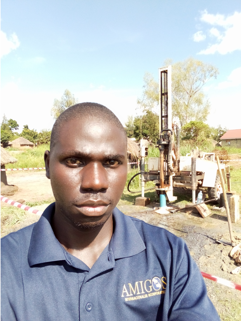 A man in a blue shirt is taking a selfie in front of a machine.