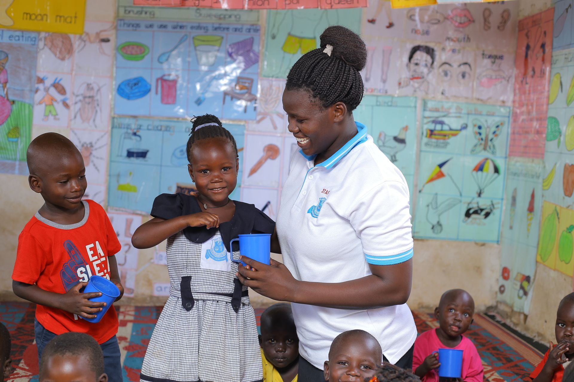 A woman is standing next to a group of children in a classroom.