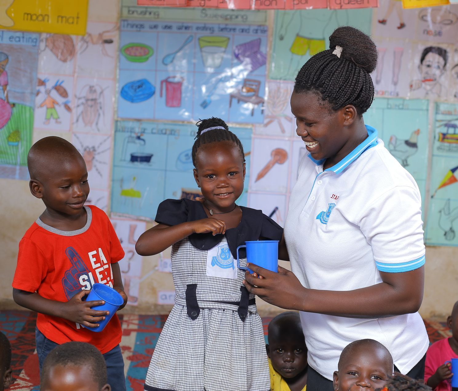 A woman is standing next to a group of children in a classroom.