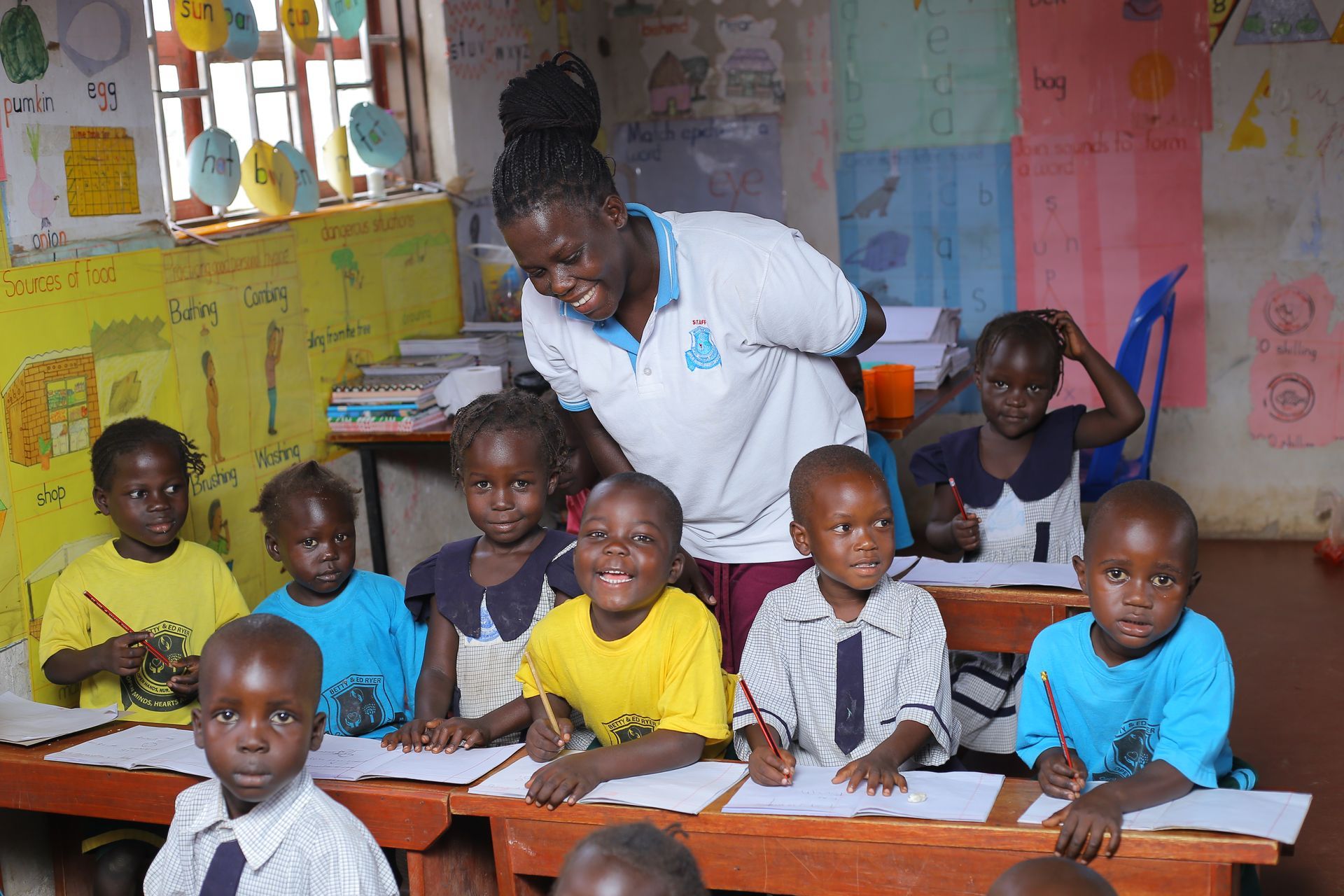 A teacher is standing in front of a group of children in a classroom.