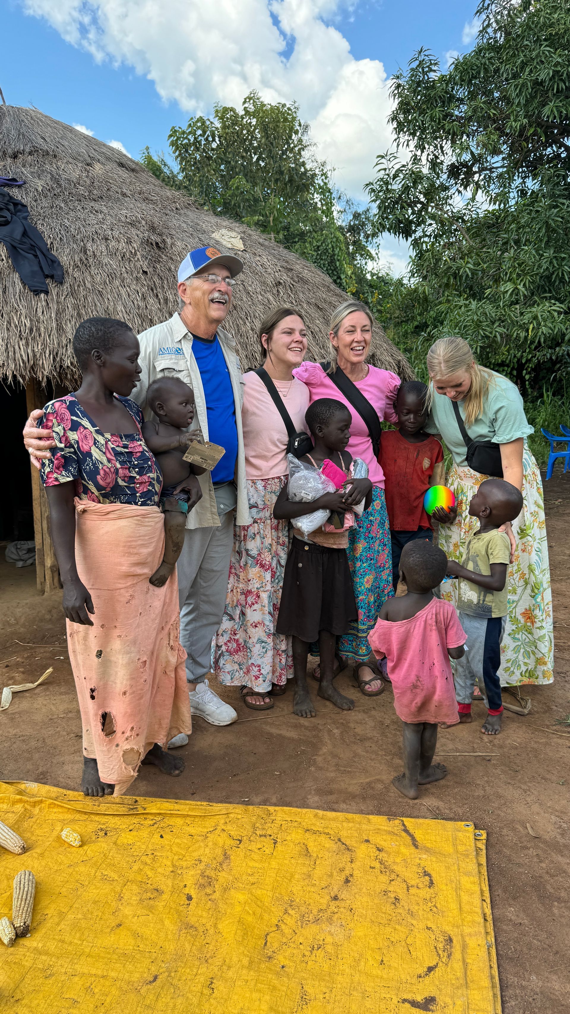 A group of people are posing for a picture in front of a thatched hut.