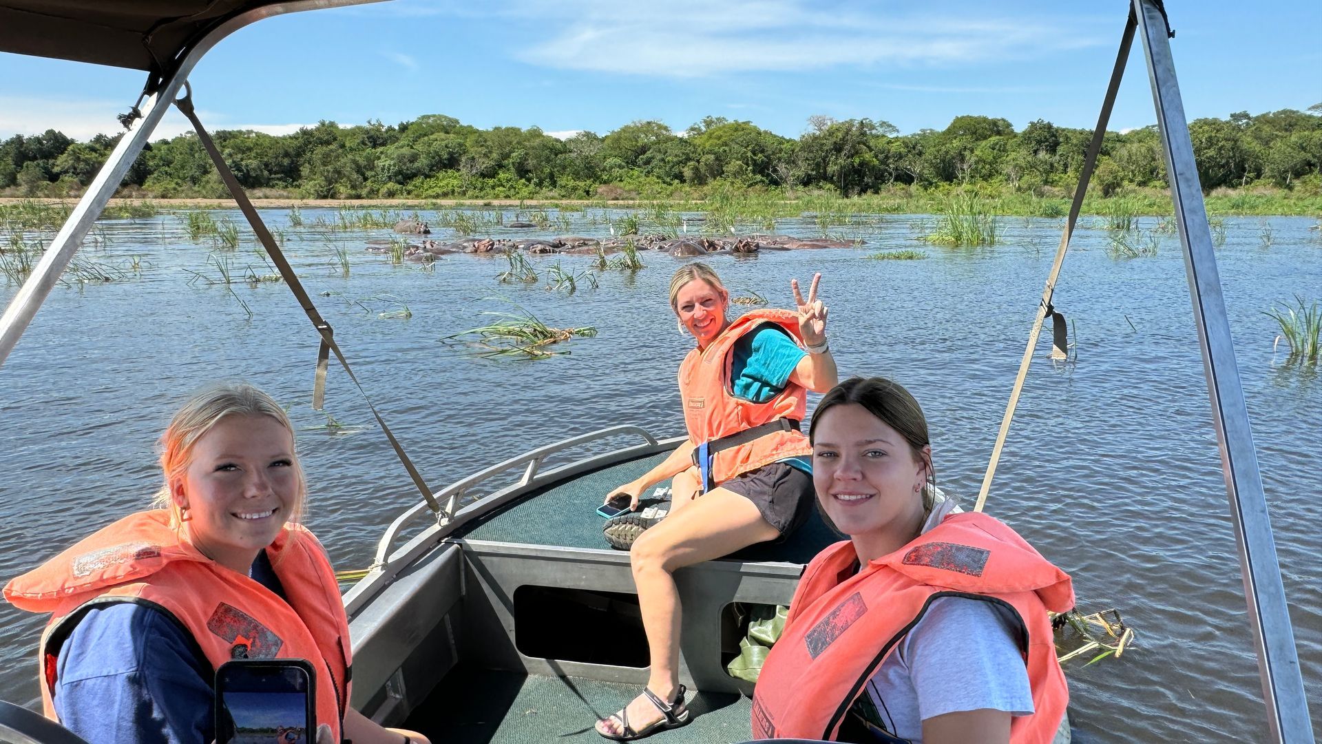 Three women wearing life jackets are sitting on a boat in the water.