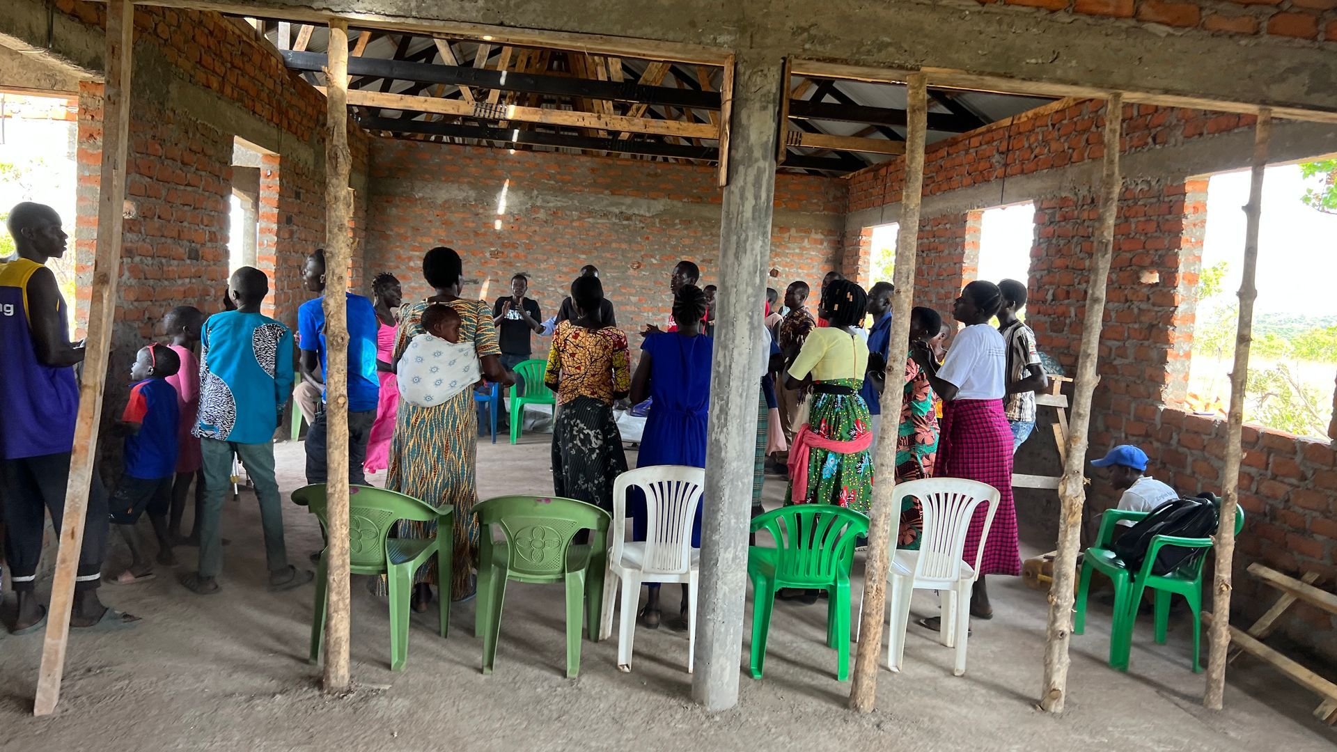 A group of people are sitting in chairs in a room under construction.