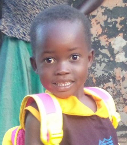 Young child in school uniform and backpack smiles, standing outside.