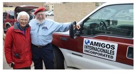 A man and woman standing next to a amigos internationales ambulance