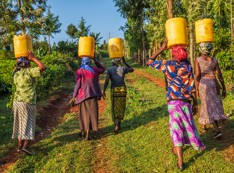 a group of women are carrying buckets of water on their heads .