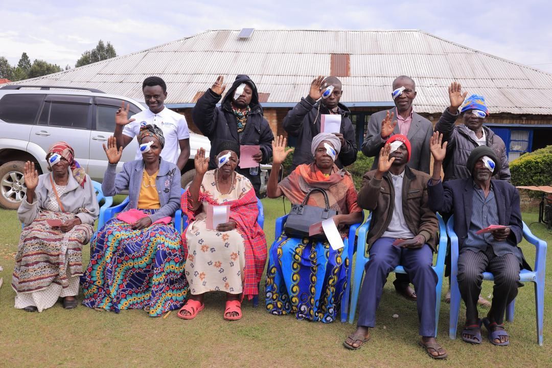 A group of people wearing sunglasses are sitting in chairs in front of a building.