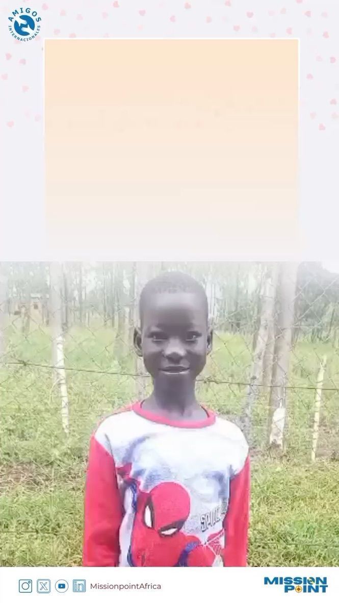 Boy in a shirt smiles. He stands outside in front of a fence and trees.