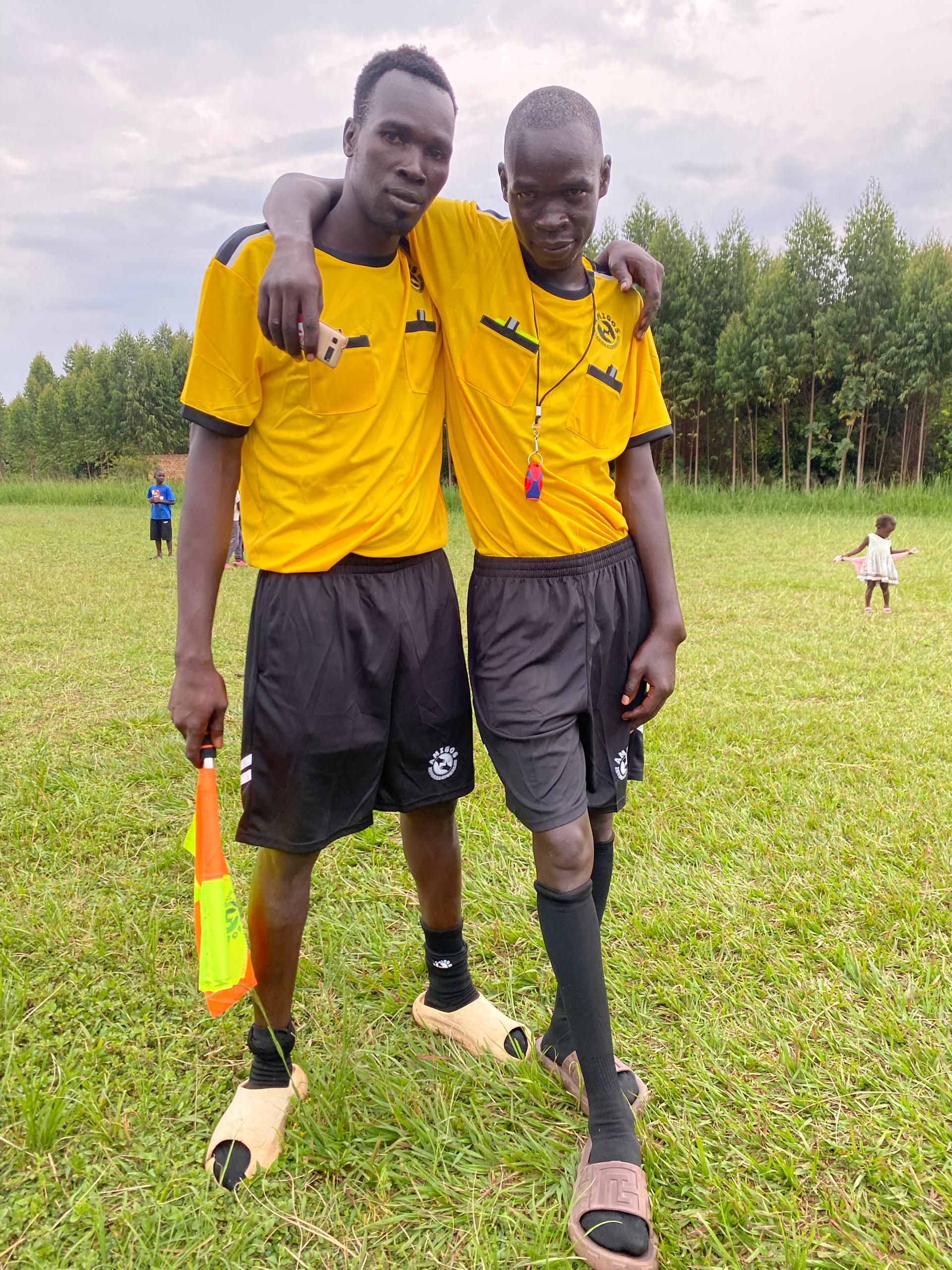 Two men are standing next to each other on a soccer field.