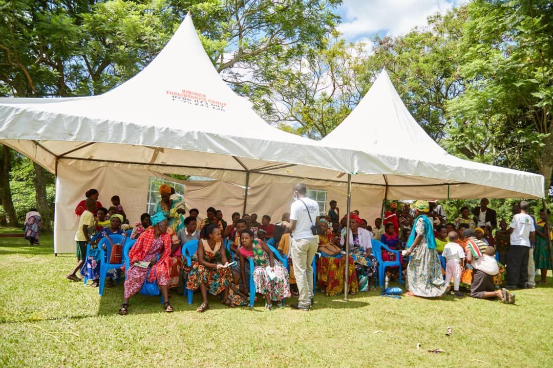 A group of people are sitting under a tent in a park.