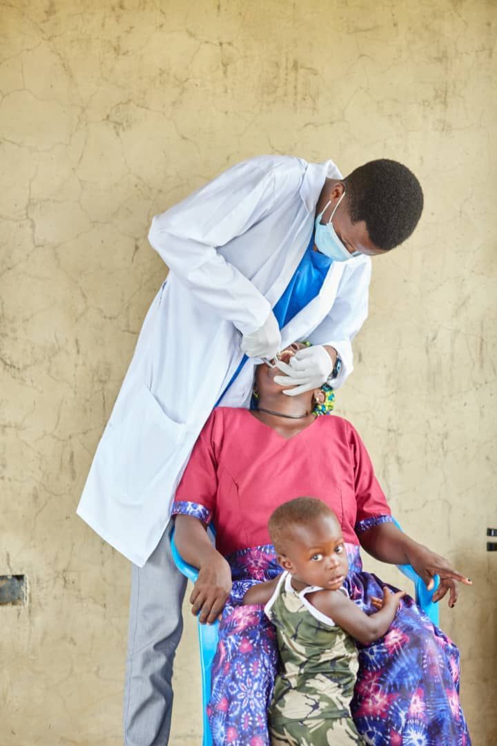 A doctor is examining a woman 's teeth while a child sits next to her