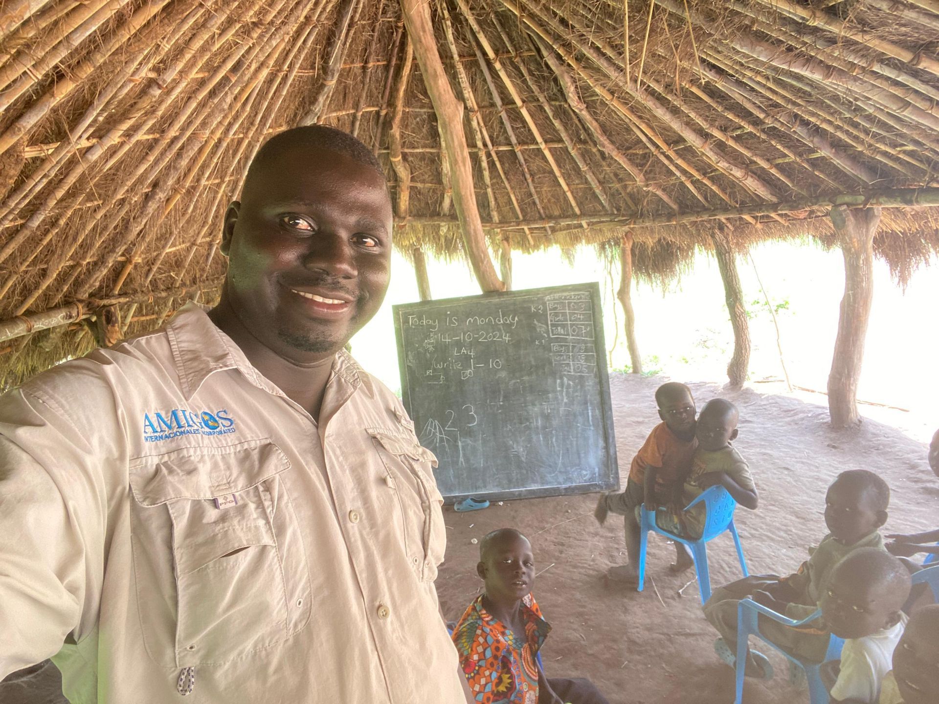 Patrick is taking a selfie in a hut with children at Providence School.