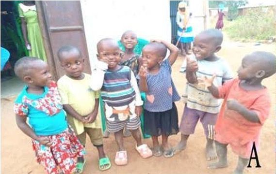 Group of young children smiling and looking at the camera outdoors, near a building.