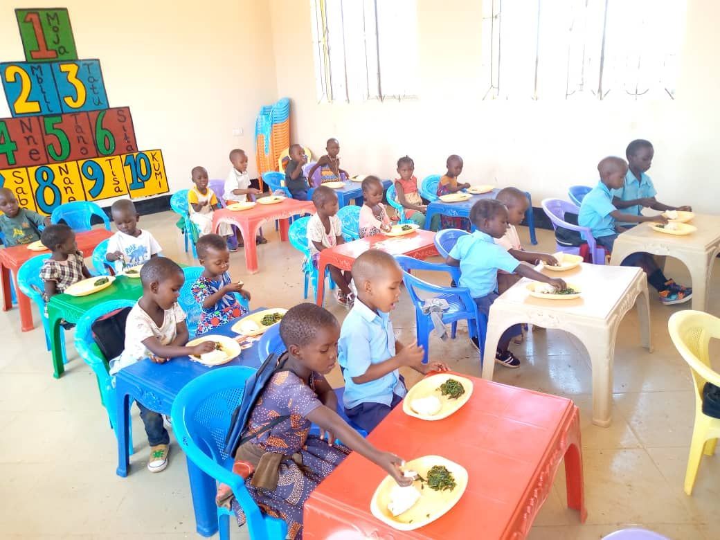 A group of children are sitting at tables eating food.