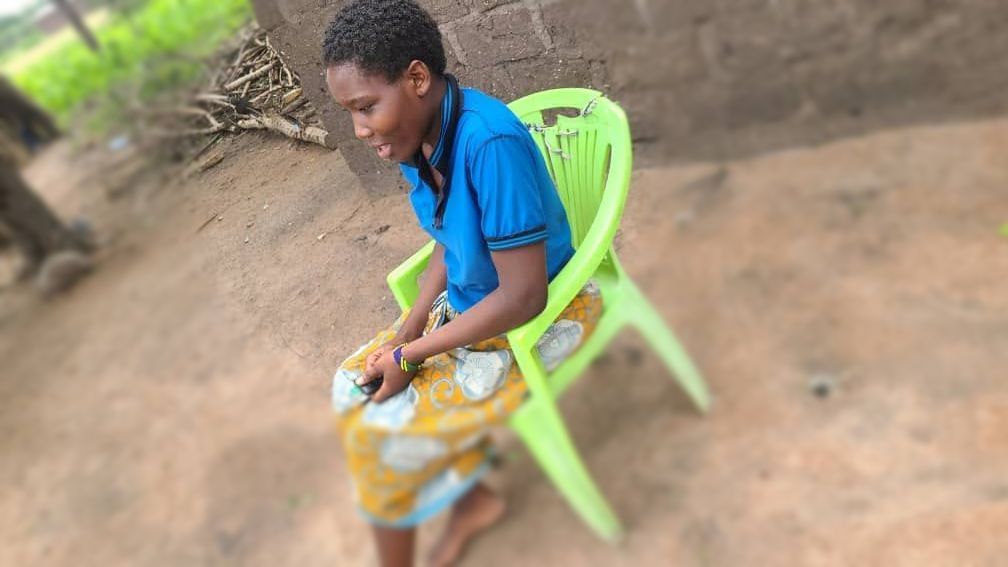 Neema, a young girl is sitting in a green chair unable to walk clearly.