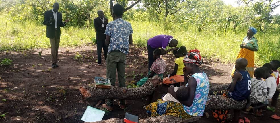 A group of people are sitting on a log in a field.