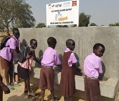 A group of children are washing their hands under a sign.