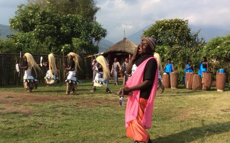 A man in a pink shirt is dancing in a field with other people.