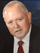 A man in a suit and tie is looking at the camera.