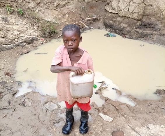 Child getting nasty water from water hole